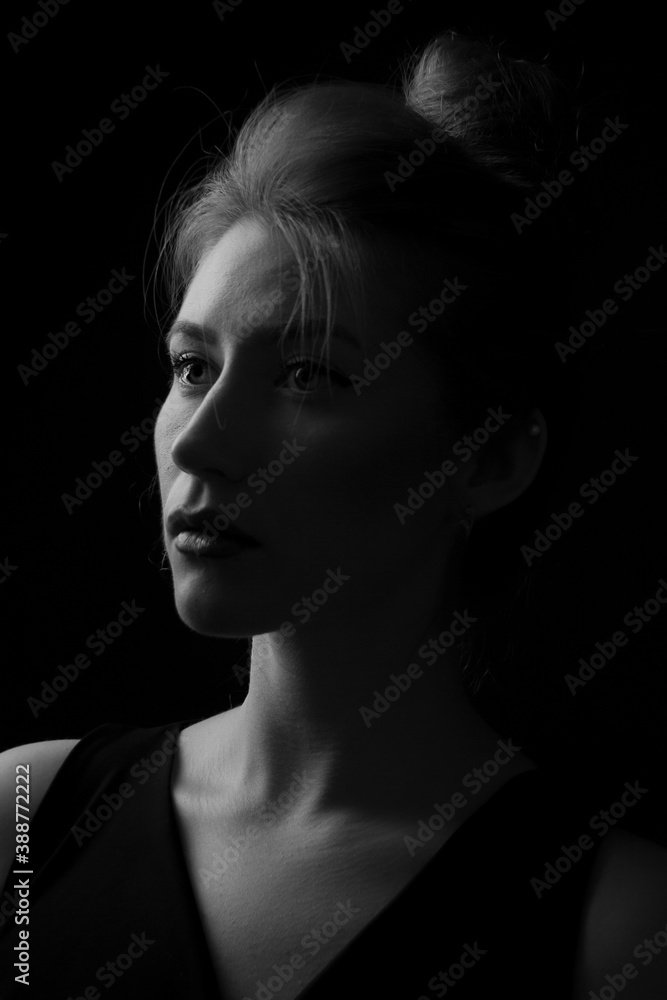 Black-and-white studio portrait of a beautiful and serious young woman.