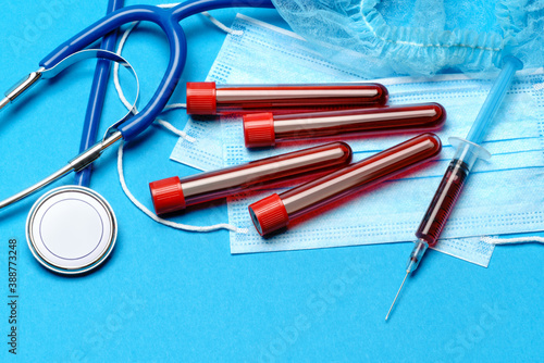 Medical lab concept - Group of Covid-19 blood samples in test tubes and syringe on blue background