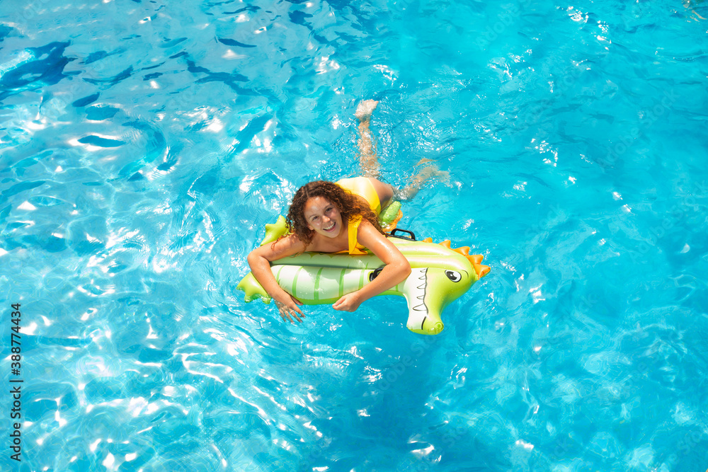 View from above of happy little girl swim on inflatable green matrass