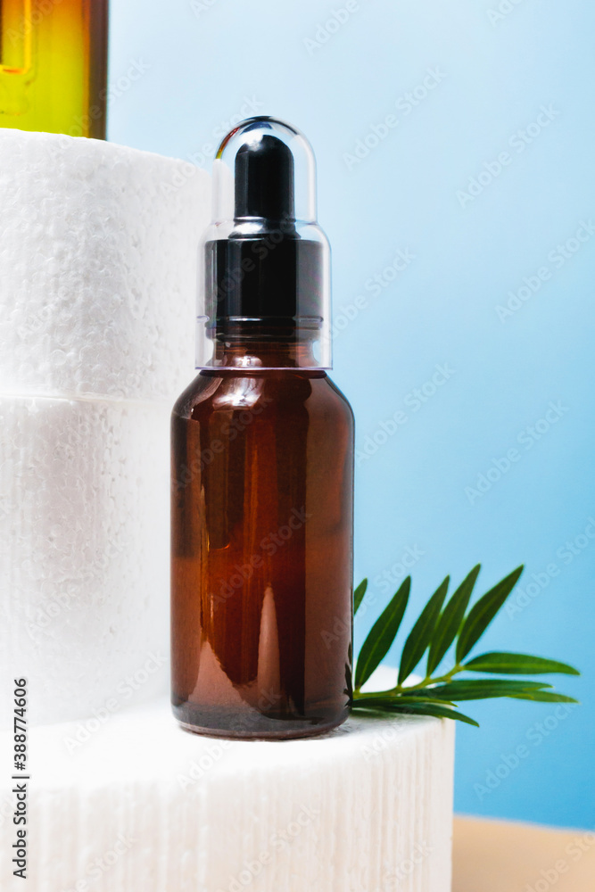 Dark Glass Bottle with Pipette Essential Oil, Serum on Blue Background. Face, Skin care Beauty closeup on podium. Dark Glass Bottle with Pipette Essential Oil, Serum on Blue Background. Face, Skin care Beauty closeup on podium.