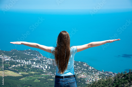 Happy woman standing on a mountain with her arms up in the air feeling happy and free.