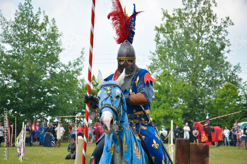 A rider in armor with a spear on a horse. The action takes place at a medieval festival.