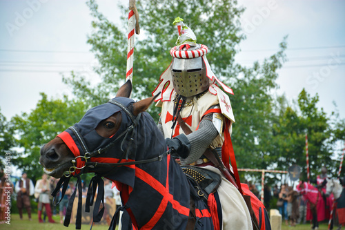 A rider in armor with a spear on a horse. The action takes place at a medieval festival.