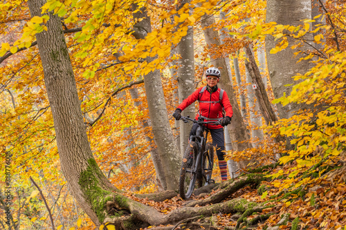 sympathetic active senior woman  riding her electric mountainbike in the gold colored autumn forests of the Swabian Alb