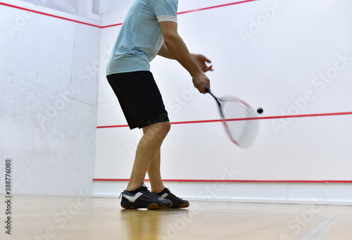 Squash player in action reaching on squash court. Out of focus, possible granularity, motion blur