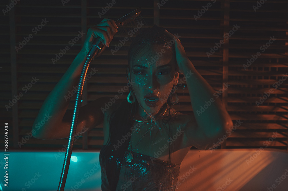 portrait of a beautiful Asian sad brunette in a hotel bathroom with neon lighting