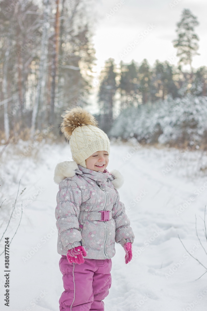 Portrait of little girl is snowy forest in winter.