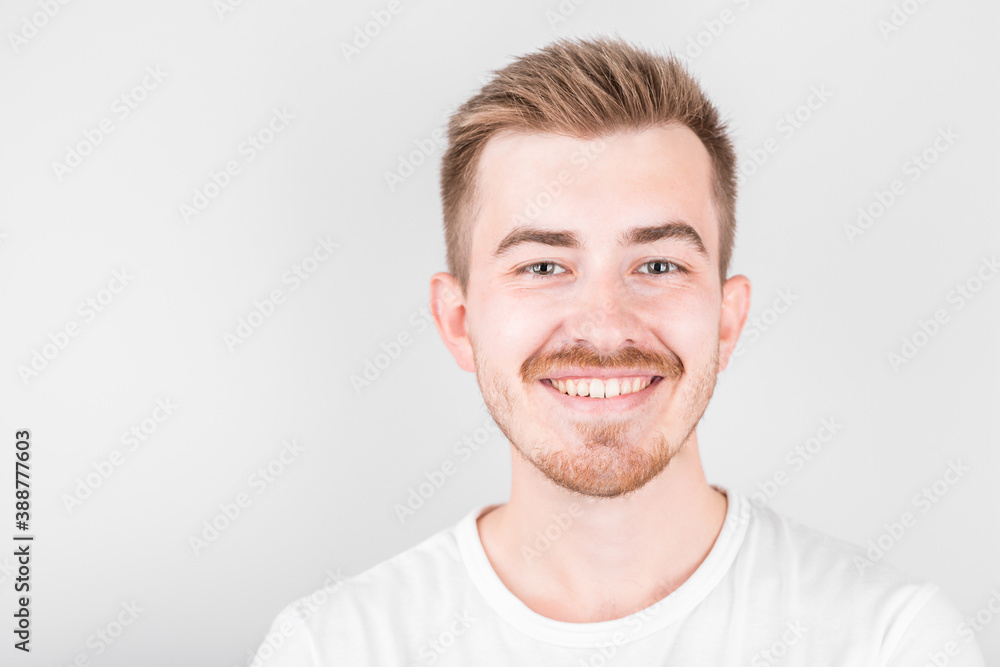 Fototapeta premium Confident young handsome man in white shirt smiling while standing against white background