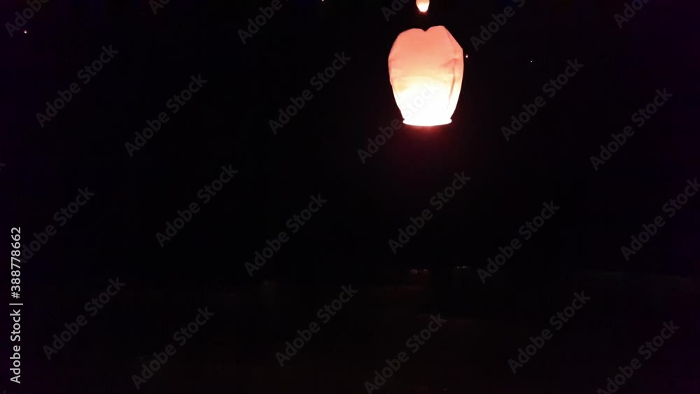 Woman releases a fire sky lantern in the air at night Woman releases a fire sky lantern in the air at night