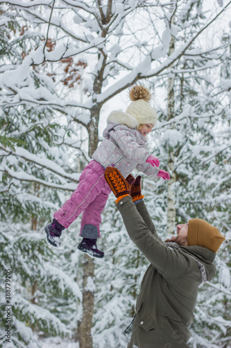 Handsome young dad and his little cute daughter are having fun outdoor in winter. Enjoying spending time together in snowy forest.