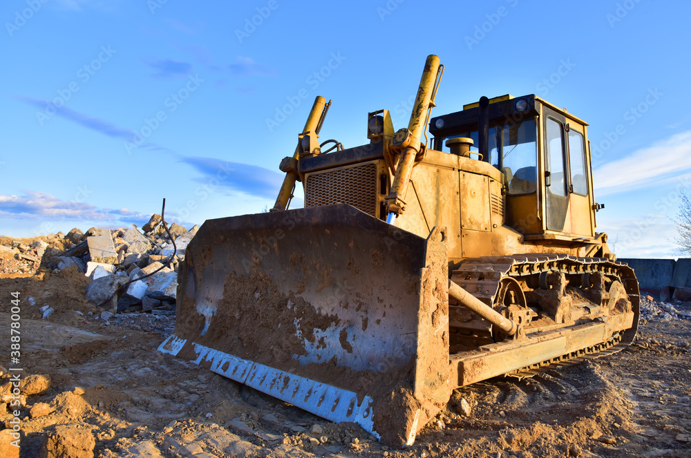 Bulldozer at landfill for work concrete demolition waste. Salvaging and recycling construction materials. Dozer destroys concrete of the old structures on construction site