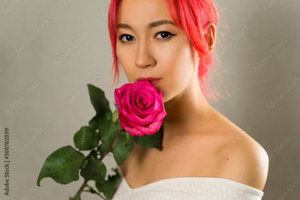 a Asian woman with creative hair coloring bright red, pink. beautiful young girl with a rose in her hand and scarlet hair
