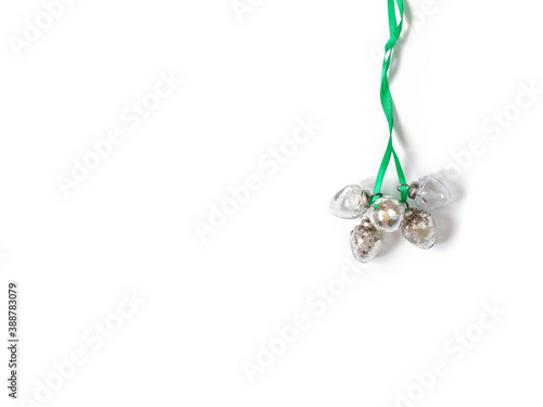 A bunch of Christmas glass balls tied with green ribbon and isolated on a white background. Minimalist Christmas composition. Copy space.