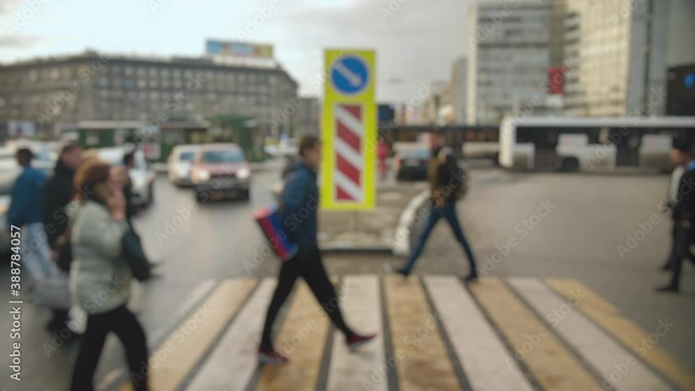 Lens blur, out of focus. A crowd of pedestrians cross the road against the background of cars on wet asphalt after rain. Crowded crosswalk. Lens blur, out of focus. A crowd of pedestrians cross the road against the background of cars on wet asphalt after rain. Crowded crosswalk.