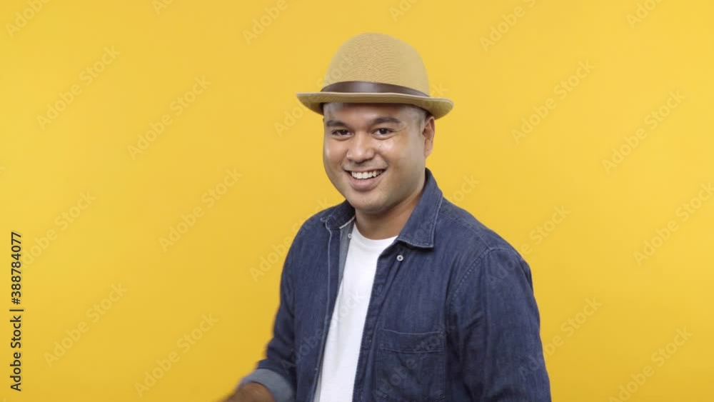 A handsome guy turning around and lift his hand point into camera with smile, sexy, cool isolated on yellow background. 4K Resolution. A handsome guy turning around and lift his hand point into camera with smile, sexy, cool isolated on yellow background. 4K Resolution.