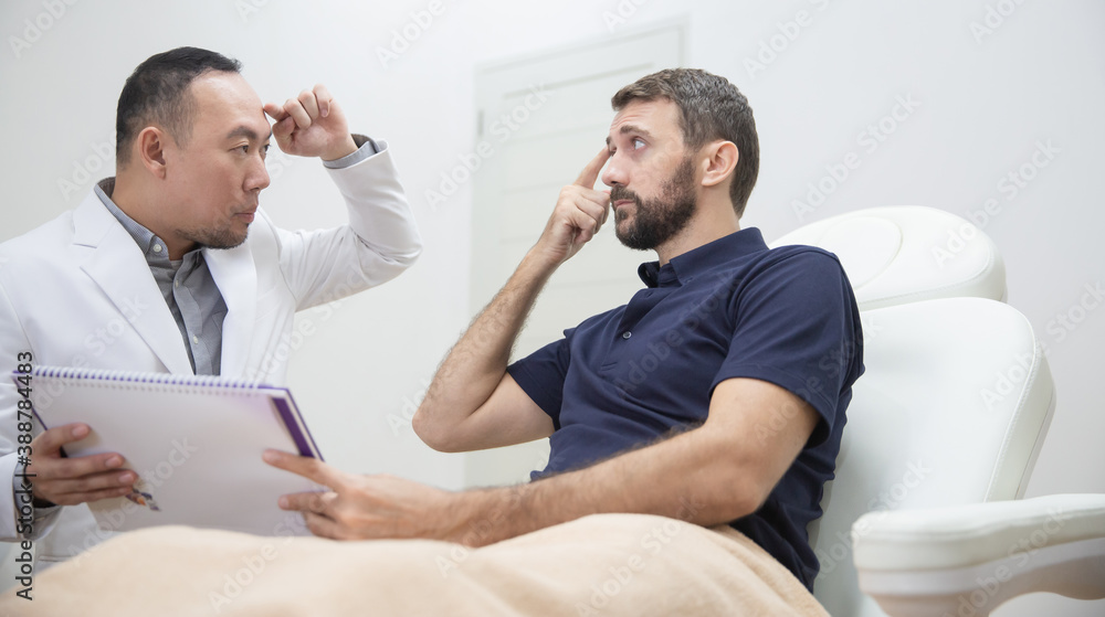 Young caucasian man in beauty salon consults with beautician on anti-aging treatments. Doctor points on fine lines and wrinkles on client's face Young caucasian man in beauty salon consults with beautician on anti-aging treatments. Doctor points on fine lines and wrinkles on client's face