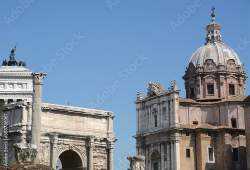 In the center of Rome, the ancient Roman Forum with the Septimius Severus Arch and the Baroque facade of the Saints Luca e Martina church.