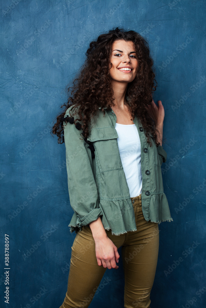 young pretty woman with curly brunette hair posing cheerful on blue background, lifestyle people concept young pretty woman with curly brunette hair posing cheerful on blue background, lifestyle people concept