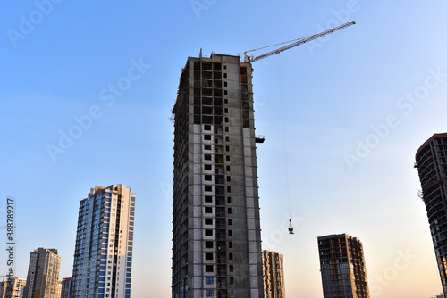 Tower crane in action at construction site. Construction of skeleton of new modern residential buildings. Preparing to pour of concrete into formwork. Erection multi-storey residential building