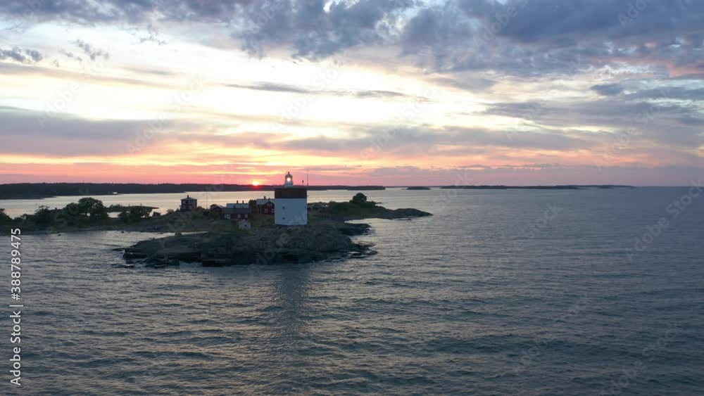 Amazing sunset over the sea & and remote island with active lighthouse & red cabins Amazing sunset over the sea & and remote island with active lighthouse & red cabins