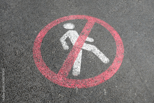 White road markup signal on concrete asphalt. Transportation restrictions on the way. No pedestrians allowed, no walking, driving and riding bicycles only. Red painted crossed sign with person inside. © Juliet Dreamhunter