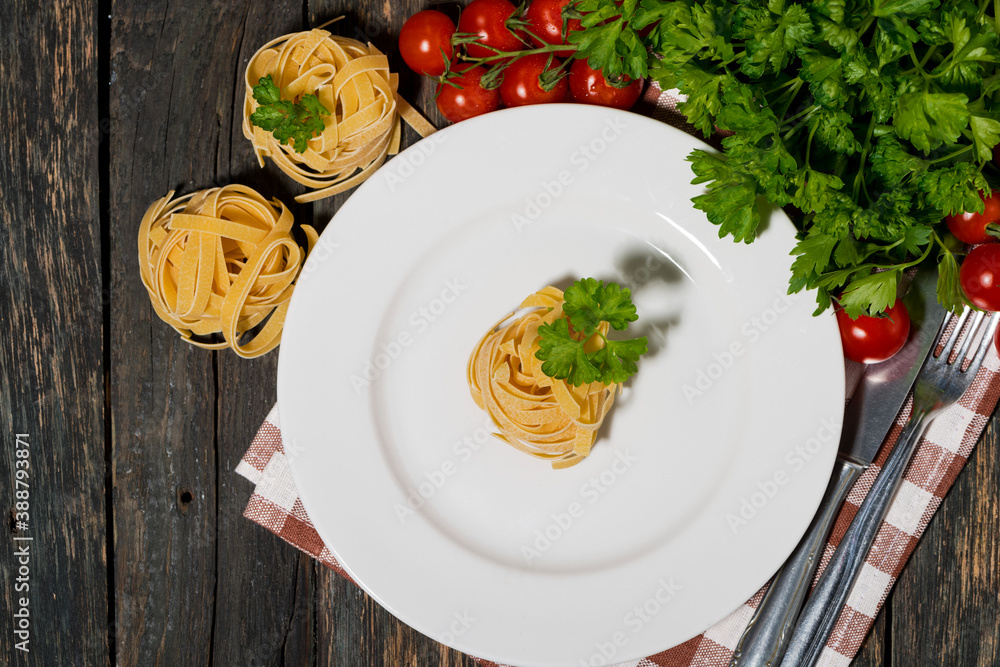 table setting with white plate, pasta and vegetables on a wooden table table setting with white plate, pasta and vegetables on a wooden table
