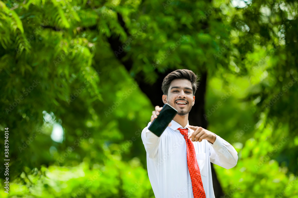 Copy space on his smart phone.Confident young Indian man showing his smart phone Copy space on his smart phone.Confident young Indian man showing his smart phone