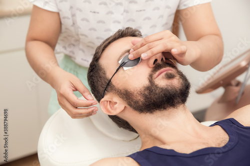 Handsome young man preparing for cosmetic laser procedure wearing protection glasses. Healthcare, wellness and medicine