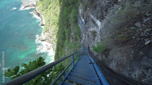 Bali Nusa Penida Indonesia - Dangerous Steep Blue Stairs with Beautiful View of Ocean and Rocks Below to Peguyangan Waterfall photo