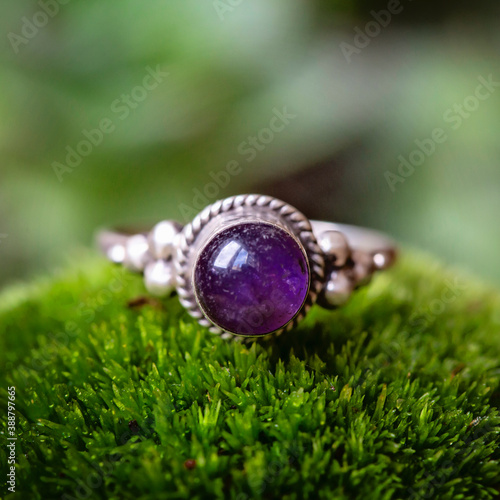 Sterling silver ring with amethyste gemstone on green moss background photo