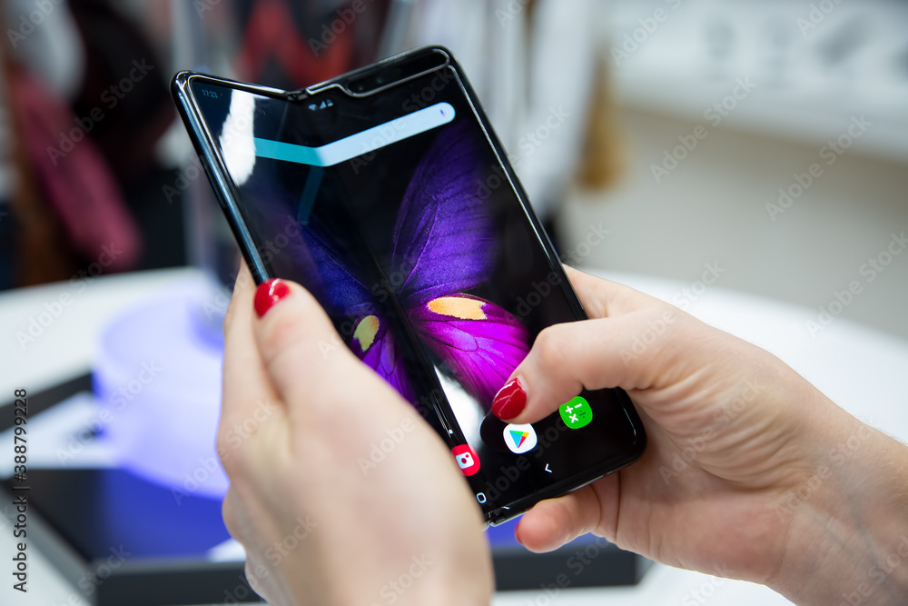 Moscow, Russia - October 04, 2019: female hands holding a new flagship  smartphone Samsung Galaxy Fold with flexible display. close up. backgtound  in blur Photos | Adobe Stock