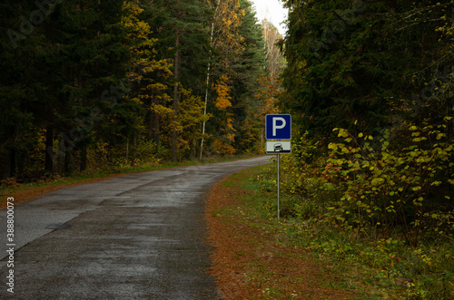 In the autumn in the forest asphalt road with a parking sign