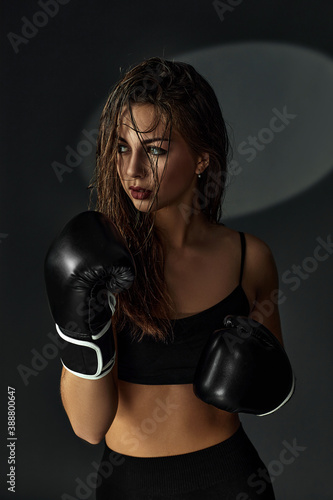 portrait of gorgeous confident sporty brunette woman in boxing gloves on studio background © producer