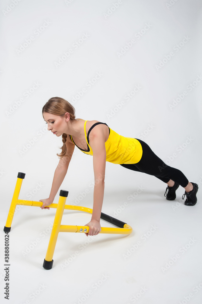 Obraz premium Woman doing exercises with high yellow floor bars on a white background