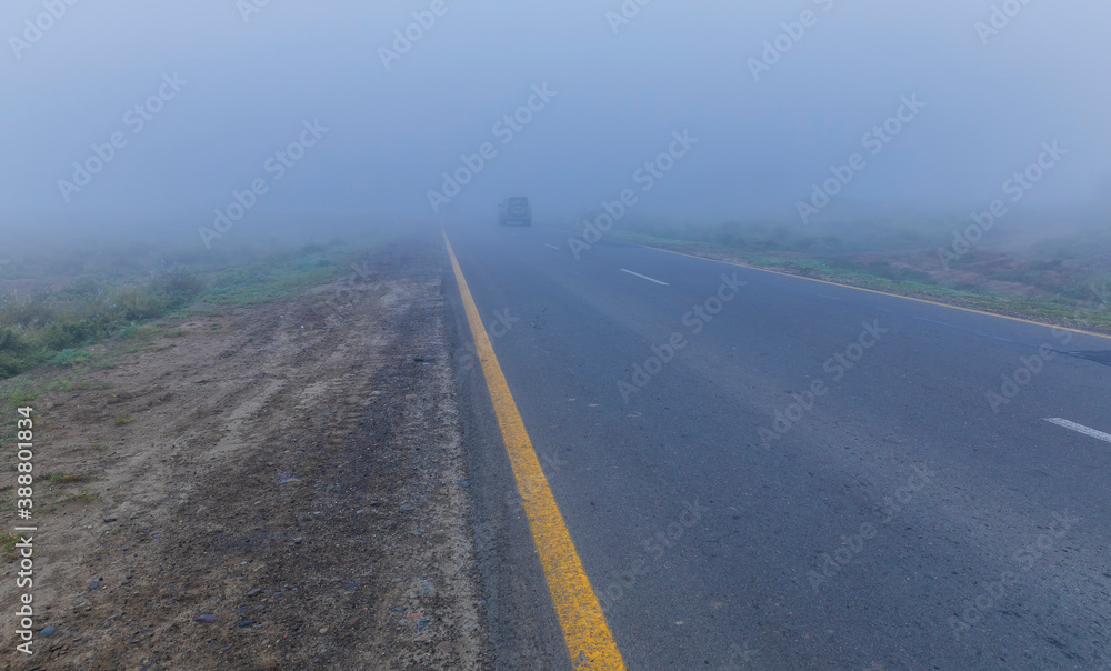 Asphalt road leaving in autumn fog