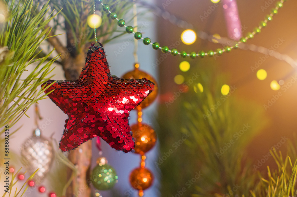 New Year and Christmas toy in a shape of red star hanging on a Christmas tree surrounded by other toys
