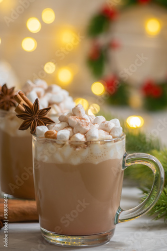 Vertical image of spiced christmas drink latte with marshmallows on the celebration table with cinnamon and anise