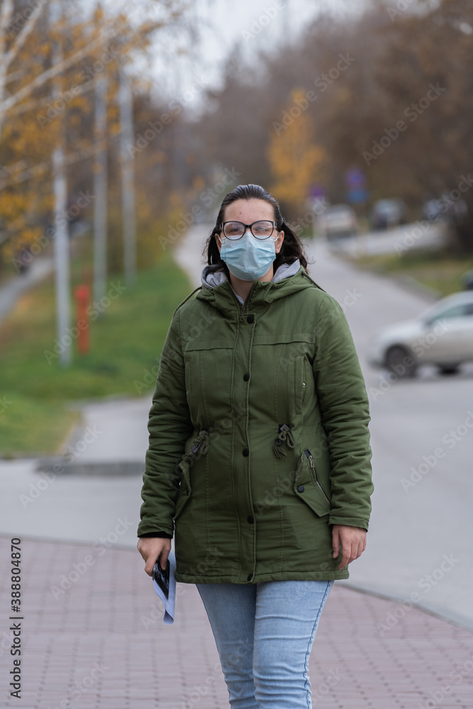 A masked girl is walking along the street. Coronavirus infection (COVID-19) A masked girl is walking along the street. Coronavirus infection (COVID-19)