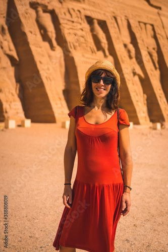 A young tourist in red dress visiting the Temple of Nefertari near Abu Simbel in southern Egypt in Nubia next to Lake Nasser. Temple of Pharaoh Ramses II, travel lifestyle © unai