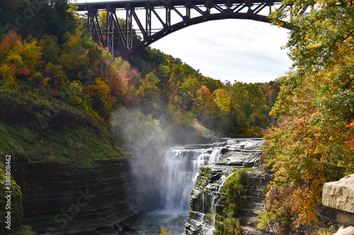 A waterfall with fall foliage and a bridge overhead
