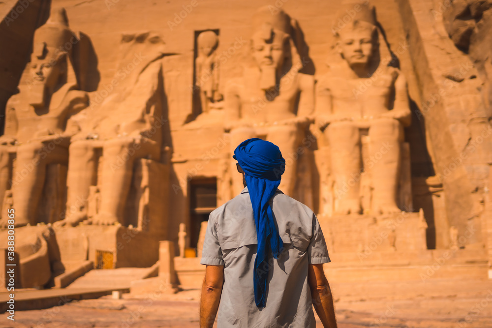 A young tourist in a blue turban looking at the Abu Simbel Temple in southern Egypt in Nubia next to Lake Nasser. Temple of Pharaoh Ramses II, travel lifestyle