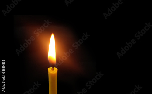 Light of yellow candle on black background.