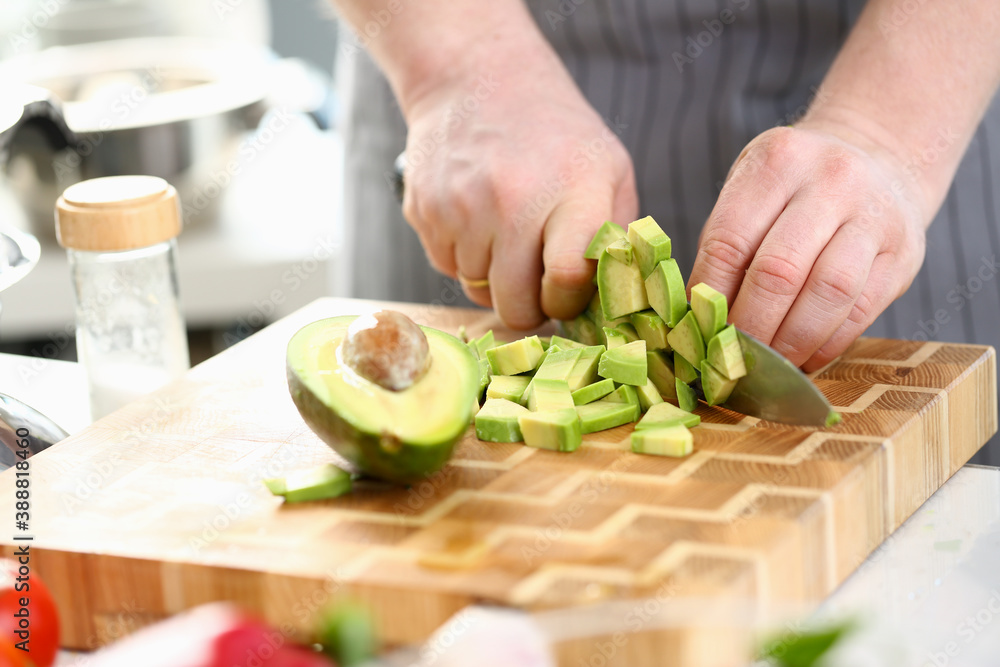 Chef Hands Cutting Dieting Tropical Fruit Avocado. Man Chopping Exotic Ingredient with Sharp Knife on Wooden Cutting Board. Male Cooking Organic Dish in Kitchen. Home Culinary Horizontal Photography