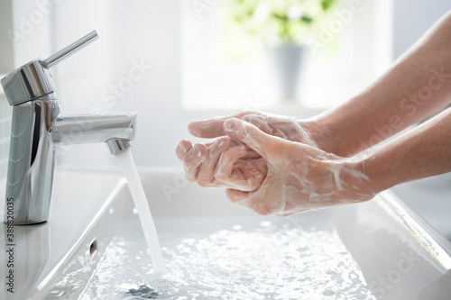 Close up teenage boy washing hands with soap and water at sink photo