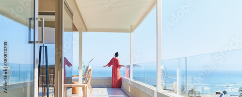 Woman in long dress enjoying sunny scenic ocean view on luxury balcony photo
