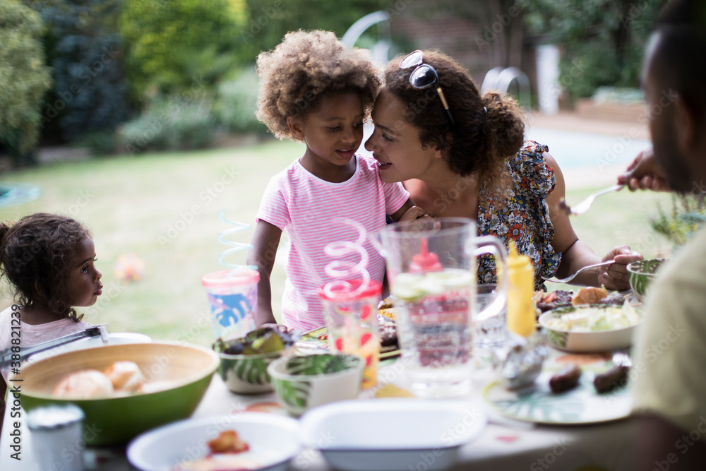 Mother and daughter enjoying backyard barbecue at patio table Mother and daughter enjoying backyard barbecue at patio table