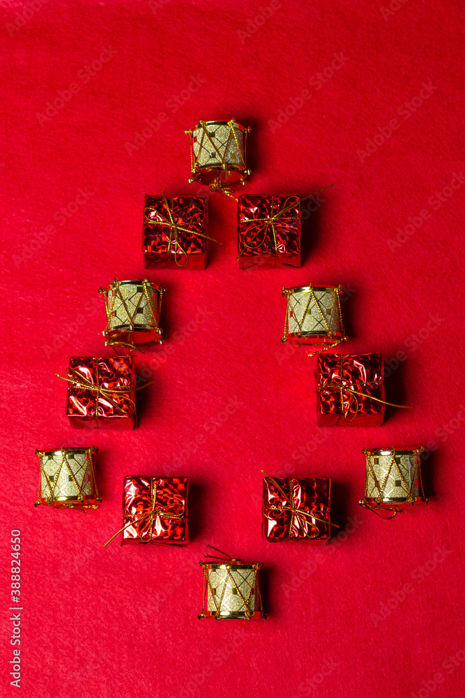 Christmas decorations on a red background. Christmas tree made of Christmas decorations. Holiday decorations. Red gift boxes. Golden game drums. Christmas concept.