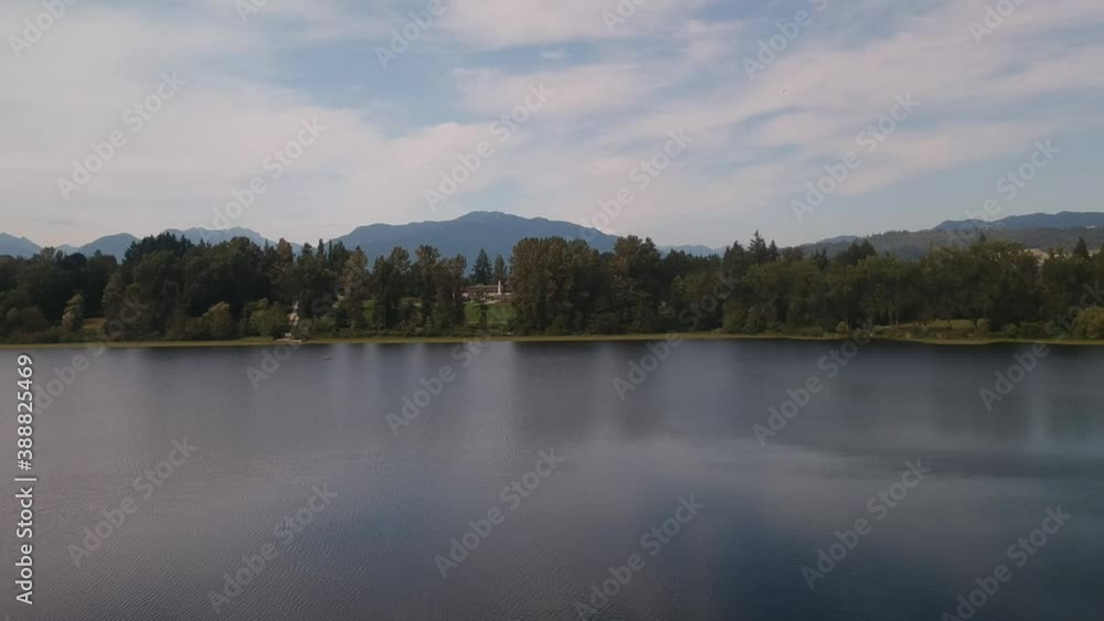 aerial rise dolly roll over calm lake pond around a lush green forest valley mountain with tranquil reflections on the water and the foliage peaceful environment fir pine maple oak trees aerial rise dolly roll over calm lake pond around a lush green forest valley mountain with tranquil reflections on the water and the foliage peaceful environment fir pine maple oak trees