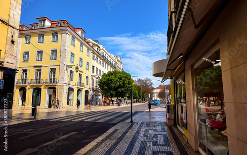 Lisbon Portugal. Empty wide street with storefront shop and yellow building. Scenic cityscape with blue sky. © Yasonya
