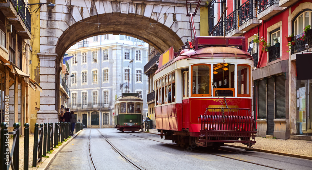 Lisbon, Portugal. Vintage red retro tram on narrow bystreet tramline in Alfama district of old town. Popular touristic attraction of Lisboa city. Public tramways trasport.